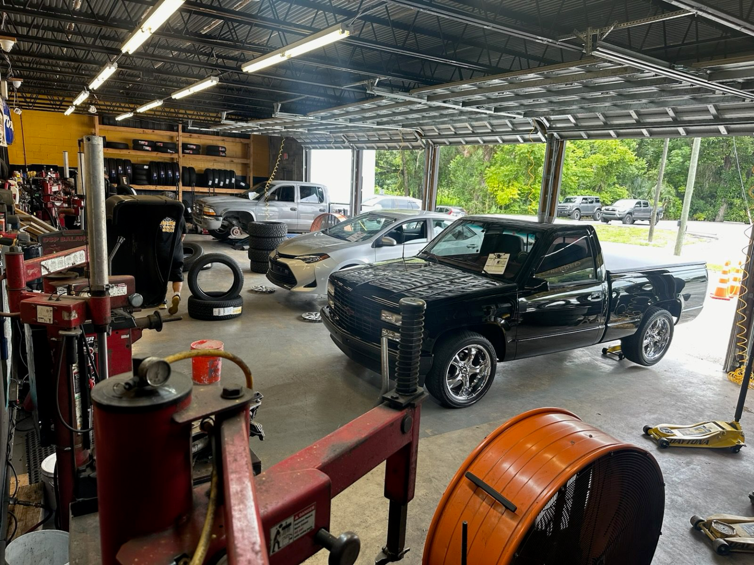 Inside Izzy's Tires shop — bays with lifts, tire racks, and vehicles being serviced